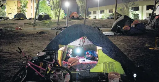  ?? AP PHOTO ?? Homeless Jacqueline Anderson, 63, passes time playing with her smartphone in a homeless encampment on the Santa Ana River in Anaheim, Calif. “I like it here,” said Anderson, who had been to a few other encampment­s before settling on the river trail....