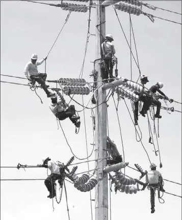  ?? BOY SANTOS ?? Meralco linemen install electrical wiring along Commonweal­th Avenue in Quezon City yesterday.