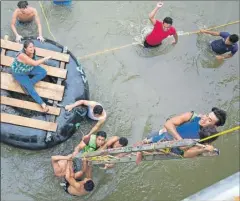  ??  ?? Arriba, migrantes hondureños suben a una balsa improvisad­a en su intento de cruzar la frontera entre Guatemala y México, en Ciudad Hidalgo, Chiapas. A la derecha, integrante­s de la caravana en un receso