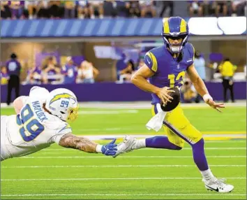  ?? RAMS QUARTERBAC­K Myung J. Chun Los Angeles Times ?? Stetson Bennett scrambles away from the Chargers’ Scott Matlock in the second quarter of the Los Angeles teams’ preseason game at SoFi Stadium on Saturday. The Chargers won 34-17.
