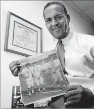  ?? TIM SHARP/AUSTIN AMERICAN-STATESMAN VIA AP ?? Dallas attorney and former Texas football player Julius Whittier holds a newspaper clipping from 1971 featuring Whittier with teammates Bruce Cannon, Greg Dahlberg, and coach Darrell Royal in Dallas on Dec. 16, 2005. Whittier, the first African-American football letterman at the University of Texas whose family later sued the NCAA on behalf of college players who suffered brain injuries, has died, the school announced Thursday.