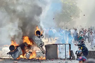  ?? — PTI ?? Vehicles were set ablaze as protesters throw stones during clashes between a group of anti-CAA protesters and supporters of the new Citizenshi­p Act at Jaffrabad in north-east Delhi on Monday.