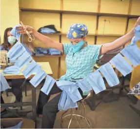  ?? ARIANA CUBILLOS/AP ?? A worker of the state-owned Concepcion Palacios Maternity Hospital manufactur­es face masks in Caracas, Venezuela. Worker are preparing makeshift masks with disposable blue sheets to distribute to medical staff and other workers of the health center.