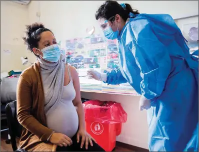  ?? (File Photo/ap/matilde Campodonic­o) ?? A nurse gives a shot of the Pfizer vaccine for covid-19 to a pregnant woman June 9, 2021, in Montevideo, Uruguay. Stories circulatin­g online incorrectl­y claim that a Pfizer document reveals that 82%-97% of pregnant women who received the company’s covid-19 vaccine “lost their babies.” The flawed calculatio­n misreprese­nts a narrow subset of data from a Pfizer database of adverse events recorded during the first two months of the vaccine rollout.