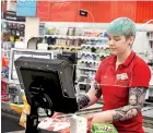  ?? (REUTERS) ?? A cashier works behind a protective plexiglass shield in Sydney, Australia, June 17.