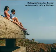  ??  ?? Holidaymak­ers sit on German bunkers on the cliffs at Pleimont