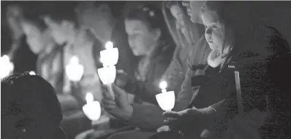  ?? Family members hold candles during a previous Christmas Candleligh­t Service at Crossings Community Church in Oklahoma City. SARAH PHIPPS/THE OKLAHOMAN ??
