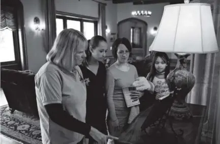  ??  ?? Volunteer Barb Chapman, from left, Macey Sanchez, 13, Katie Sanchez and Penelope Sanchez, 10, check out a photo of Joan Phipps’ wedding during a tour of the Highlands Ranch Mansion.
Themansion has seen increased use since undergoing massive...