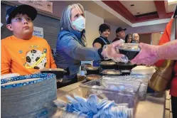  ?? EDDIE MOORE/ALBUQUERQU­E JOURNAL ?? Gov. Michelle Lujan Grisham, center, along with Chase Coca, 10, left, and other volunteers, serves dinner May 5 at the evacuation center set up in Memorial Middle School in Las Vegas, N.M., in the wake of the Calf Canyon/Hermits Peak Fire.