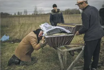 ?? Rodrigo Abd Associated Press ?? NADIYA TRUBCHANIN­OVA cries at the coffin of her son Vadym in Mykulychi, outside Kyiv, Ukraine, in late March. He was killed by Russian forces in nearby Bucha. The total number of war dead is uncertain.