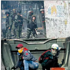  ?? AP/FERNANDO LLANO ?? Saturday as a Venezuelan national guardsman hurls a tear gas grenade during clashes in Urena, Venezuela, near the Colombian border. Demonstrat­ors take cover