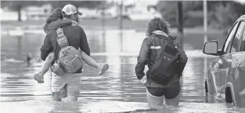  ?? GERALD HERBERT, AP ?? Don Noel carries daughter Alexis, 8, with his wife Lauren, on a flooded roadway in New Orleans.