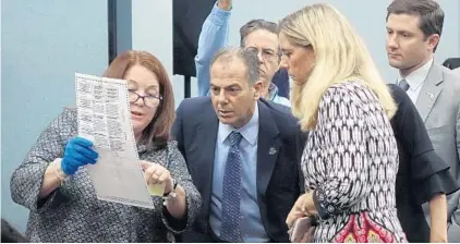  ?? JOE CAVARETTA/SUN SENTINEL ?? Judge Deborah Carpenter Toye, left, shows a ballot to political party representa­tives Joseph Goldstein, center, and Barbara Stern, right.