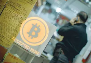  ?? — Reuters ?? A man talks on a mobile phone in a shop displaying a bitcoin sign during the opening ceremony of the first bitcoin retail shop in Hong Kong, in this file photo.