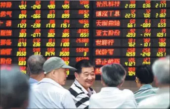  ?? SU YANG / FOR CHINA DAILY ?? Investors examine stock prices at a security brokerage in Nanjing, capital of Jiangsu province, on Wednesday.