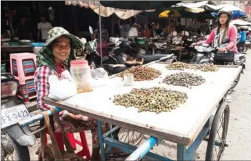  ?? ELIAH LILLIS ?? A vendor sells clams outside Phsar Kabko in Phnom Penh yesterday. In a populist gesture, Prime Minister Hun Sen abolished fees paid by similar vendors who sell their wares outside of market premises.