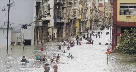  ?? RAMON ESPINOSA / THE ASSOCIATED PRESS ?? People move through flooded streets in Havana Sunday after hurricane Irma ripped through parts of Cuba. The powerful storm took roofs off houses, collapsed buildings and flooded hundreds of miles of coastline. Cuban officials warned residents to be...