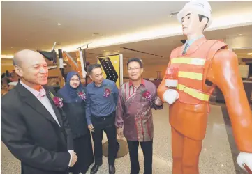  ??  ?? Julaihi (right) visits a safety exhibit. Lee is at left while state JKR director Datu Zuraimi Sabki is at second right. – Photo by Chimon Upon