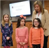  ?? TIMES photograph­s by Annette Beard ?? Students Parker Dossey, Aria Butler and Emrie Walden introduced themselves to the board as they were presented by principal Darah Bennett. A second kindergart­en student, Harper Fry, was unable to attend.