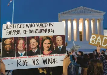  ?? JACQUELYN MARTIN /AP ?? Nikki Tran, of Washington, holds up a sign with pictures of Supreme Court Justices Clarence Thomas, Brett Kavanaugh, Samuel Alito, Amy Coney Barrett and Neil Gorsuch as demonstrat­ors protest outside of the U.S. Supreme Court on May 3 in Washington, D.C.