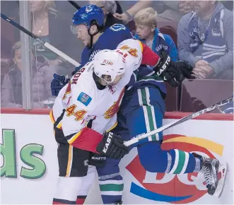  ?? THE CANADIAN PRESS ?? Flames defenceman Ryan Wilson pins Vancouver centre Cole Cassels against the boards during Saturday's pre- season game. Wilson is among four blue- liners vying for two open roster spots.