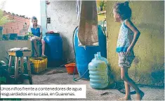  ??  ?? Unos niños frente a contenedor­es de agua resguardad­os en su casa, en Guarenas.