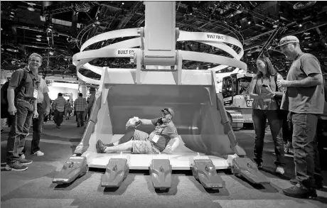  ?? REUTERS ?? A visitor sits in an eight-yard excavator bucket at the Caterpilla­r booth during the CONEXPO-CON/AGG convention at the Las Vegas Convention Center in Las Vegas, Nevada.