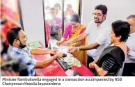  ??  ?? Minister Rambukwell­a engaged in a transactio­n accompanie­d by NSB Chairperso­n Keasila Jayawarden­a