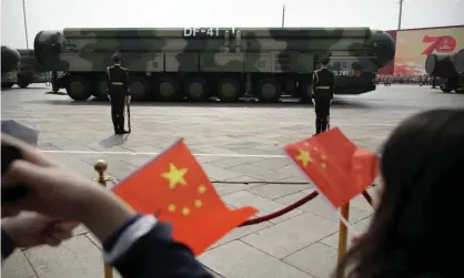  ?? Photograph: AP ?? Chinese military vehicles carrying DF-41 ballistic missiles drive past flag-waving spectators during a parade in Beijing.