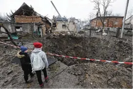  ?? MYKOLA TYS / ASSOCIATED PRESS ?? Ukrainian children look at a crater created by an explosion in a residentia­l area after Russian shelling in Lviv on Wednesday.