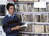  ?? Chronicle file ?? Hoe Pham looks over a Vietnamese-language book at his circa-1985 video store in Palacios.