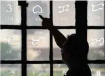  ??  ?? National Museum researcher Leo Batoon pointing to a Baybayin character etched on a glass window at the National Museum in Manila.