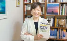  ?? Courtesy of Lee Kyung-eun ?? Lee Kyung-eun, director at Human Rights Beyond Borders and author of “The Global Orphan Adoption System,” poses with her book at her office in Seoul, May 20.