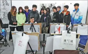  ?? ZHAO XIAOMING / FOR CHINA DAILY ?? Hopefuls watch as a teacher demonstrat­es a technique at an art studio in Jinan, Shandong province.