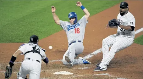  ?? Andy Cross, The Denver Post ?? Colorado catcher Tony Wolters tosses the ball to Colorado reliever Carlos Estevez after chasing down a wild pitch as Los Angeles catcher Will Smith scores in the seventh inning at Coors Field.