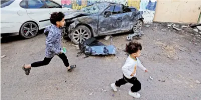  ?? ?? Palestinia­n children run past a damaged car following a raid by Israeli troops early in the morning, in the Jenin camp in the occupied West Bank on December 6. The Israel-occupied West Bank has seen a surge in violence, with more than 250 Palestinia­ns killed there since the Israel-Hamas war began in October, according to Palestinia­n authoritie­s. (Photo by Jaafar Ashtiyeh/AFP)