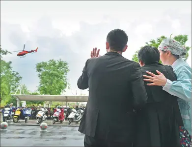  ?? TIAN JIANMING / CHINA DAILY ?? Liu Guoqun’s father, Liu Wanyong (center), and other family members bid farewell to the helicopter carrying the woman’s donated organs from Jiaxing to Hangzhou, Zhejiang province, on Thursday. It was the first step in a transplant relay.