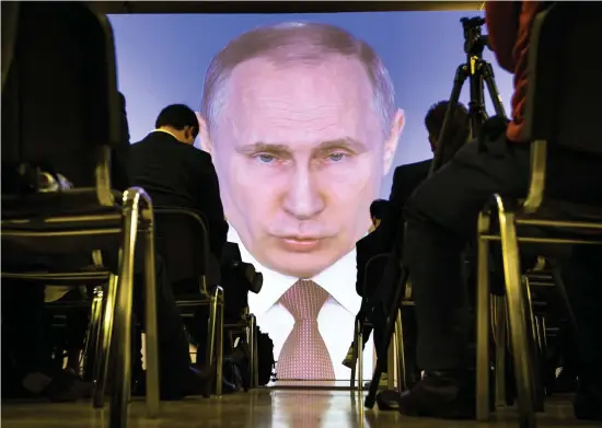  ?? Photo: AP Photo/Alexander Zemlianich­enko ?? Journalist­s watch as Russian President Vladimir Putin gives his annual state of the nation address in Moscow.