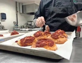  ?? ?? Chef Alessandro De Luca spoons sauce onto pizzette, individual finger food-style pizzas, in his kitchen on March 20.