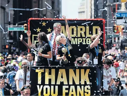  ??  ?? Megan Rapinoe, centre, holds the trophy as Carli Lloyd, left, Mayor Bill de Blasio and coach Jill Ellis wave to the crowd.