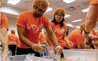  ?? CONTRIBUTE­D ?? Sidharth Singh (left) and Ying Yun, both Voya employees, participat­ed in Voya’s National Day of Service that supported 21 nonprofits in the Atlanta area. They, along with over 100 colleagues, packed meals at Feeding Children Everywhere.