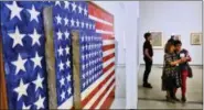  ?? RICHARD VOGEL — THE ASSOCIATED PRESS ?? Journalist­s gather around a Jasper Johns, Flag, encaustic and collage on canvas.