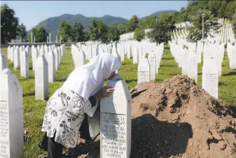  ?? Kemal Softic / Associated Press ?? A woman kisses a gravestone near Srebrenica. The recently identified remains of nine Bosniak Muslim victims of the 1995 genocide were reburied in a memorial cemetery just outside the city.