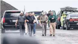  ?? DANNY ZARAGOZA/THE LAREDO MORNING TIMES VIA AP ?? Law enforcemen­t officers gather Saturday near Interstate 35 north of Laredo, Texas, where the body of a woman was found.