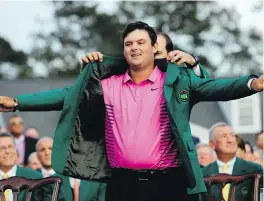  ?? DAVID PHILLIP, THE ASSOCIATED PRESS ?? Former Masters champion Sergio Garcia helps Patrick Reed with his green jacket after the final round at Augusta on Sunday.