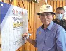  ?? — Bernama photo ?? Roland signs a plaque to officiate the opening of the KPF Collection, Processing and Packaging Centre in Ulu Tiram.