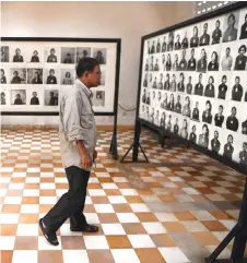  ?? — AFP file photo ?? Norng looks at portraits of victims displayed at the museum now in the former prison, where thousands of Cambodian died during the brutal 1975-79 regime, in Phnom Penh.