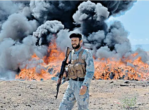  ??  ?? An Afghan soldier stands guard after a huge find of illegal drugs is set ablaze in Jalabad. A six-month operation yielded more than 14 tons of opium, heroin, hashish and alcoholic drinks