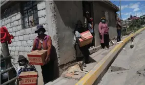  ?? Associated Press ?? ■ Residents wearing protective face masks hold food boxes distribute­d by the government during a lockdown to contain the spread of COVID-19 in this May 27 file photo taken on the outskirts of Quito, Ecuador. The coronaviru­s pandemic has brought hard times for many farmers and has imperiled food security for many millions both in the cities and the countrysid­e.