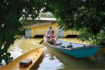  ?? ?? Two residents of Kampung Tersang in Pasir Mas, Kelantan paddle their way to check on their inundated house. – Bernama photo